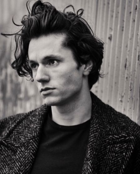 black and white picture of james wearing a black coat and messy hair 